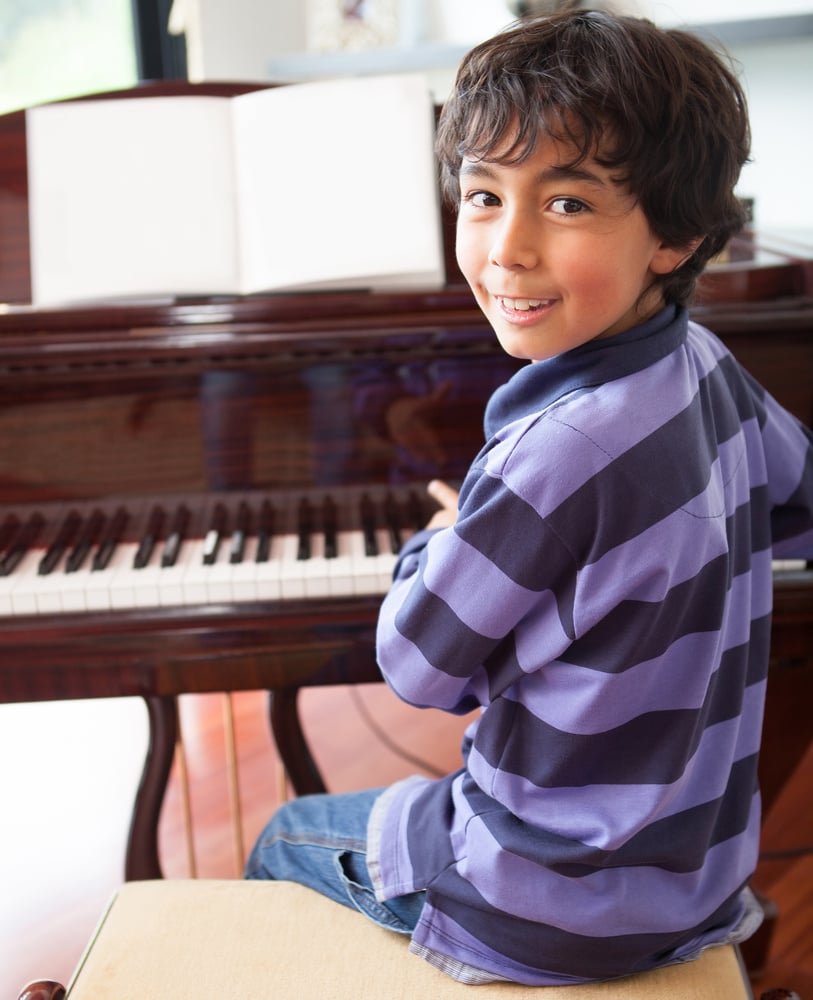 Happy boy playing the piano at home